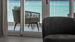 Ein modernes Zimmer mit großen Fenstern, einem grauen Sofa und Meerblick.