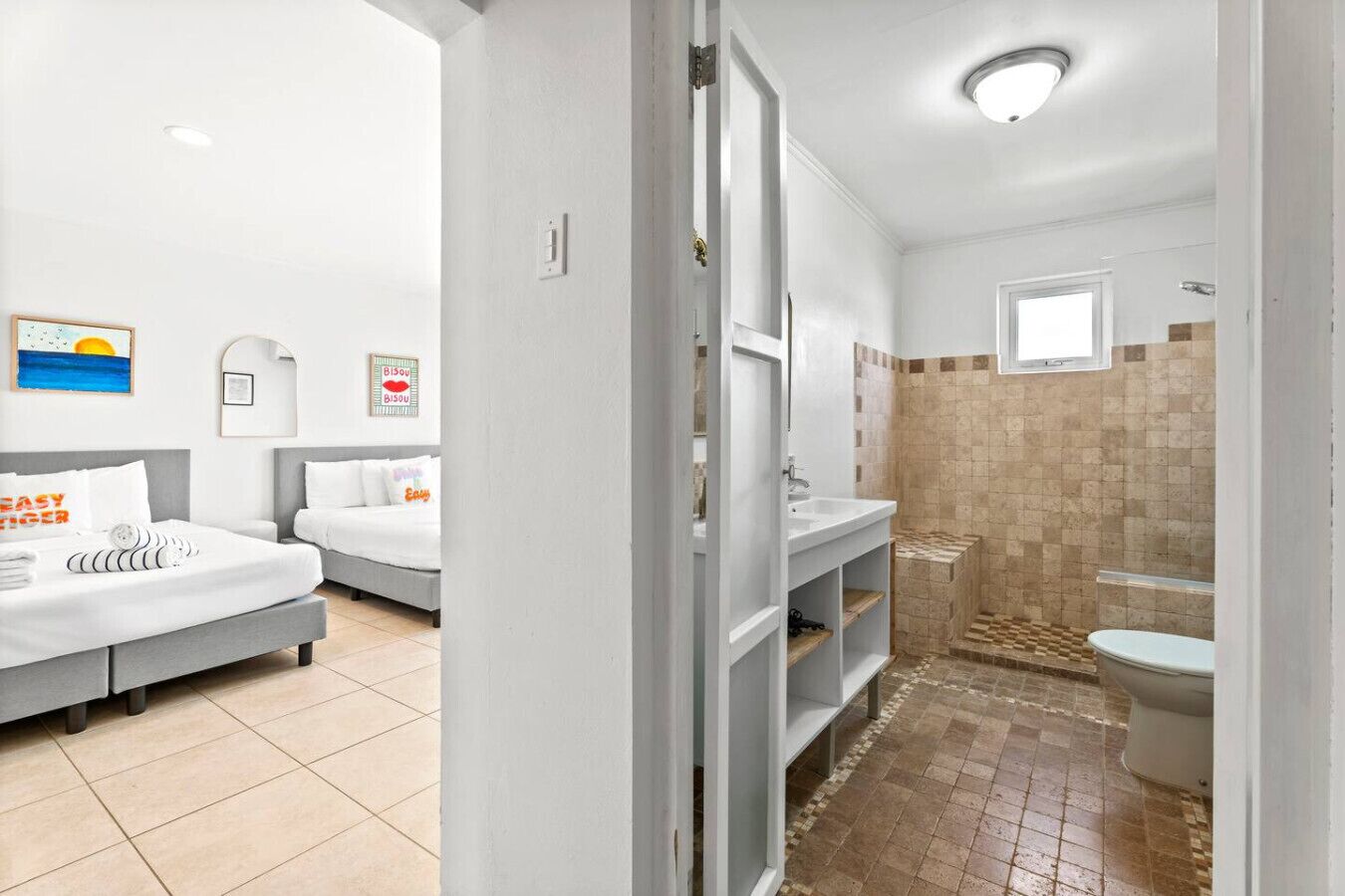Une chambre d’hôtel avec deux lits, une salle de bain avec douche et des toilettes.