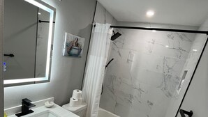 Ein modernes Badezimmer mit Waschbecken, Toilette und Badewanne, alles in Weiß.