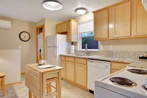 Una cocina con armarios de madera, un refrigerador, un lavavajillas, una estufa y una ventana con persianas.
