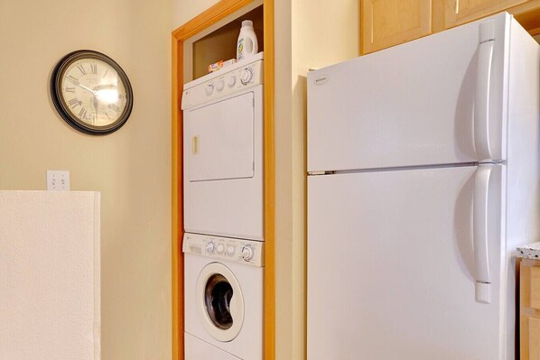 Un cuarto de lavado con lavadora, secadora y refrigerador.