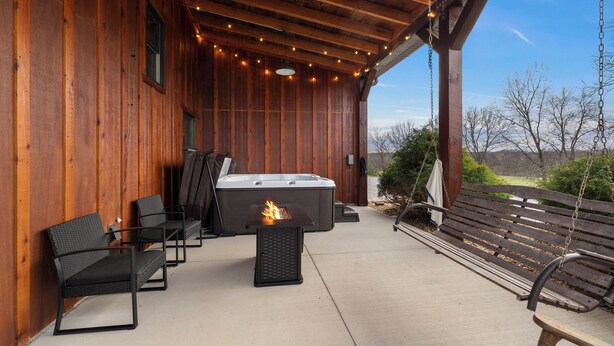 Een terras buiten met houten wanden, een hottub en zitgedeeltes.