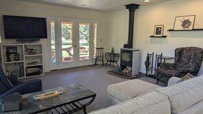 A living room with a fireplace, a television, and a sofa. - Modern house on the AuSable w/ canoe & swimming access (Grayling)
