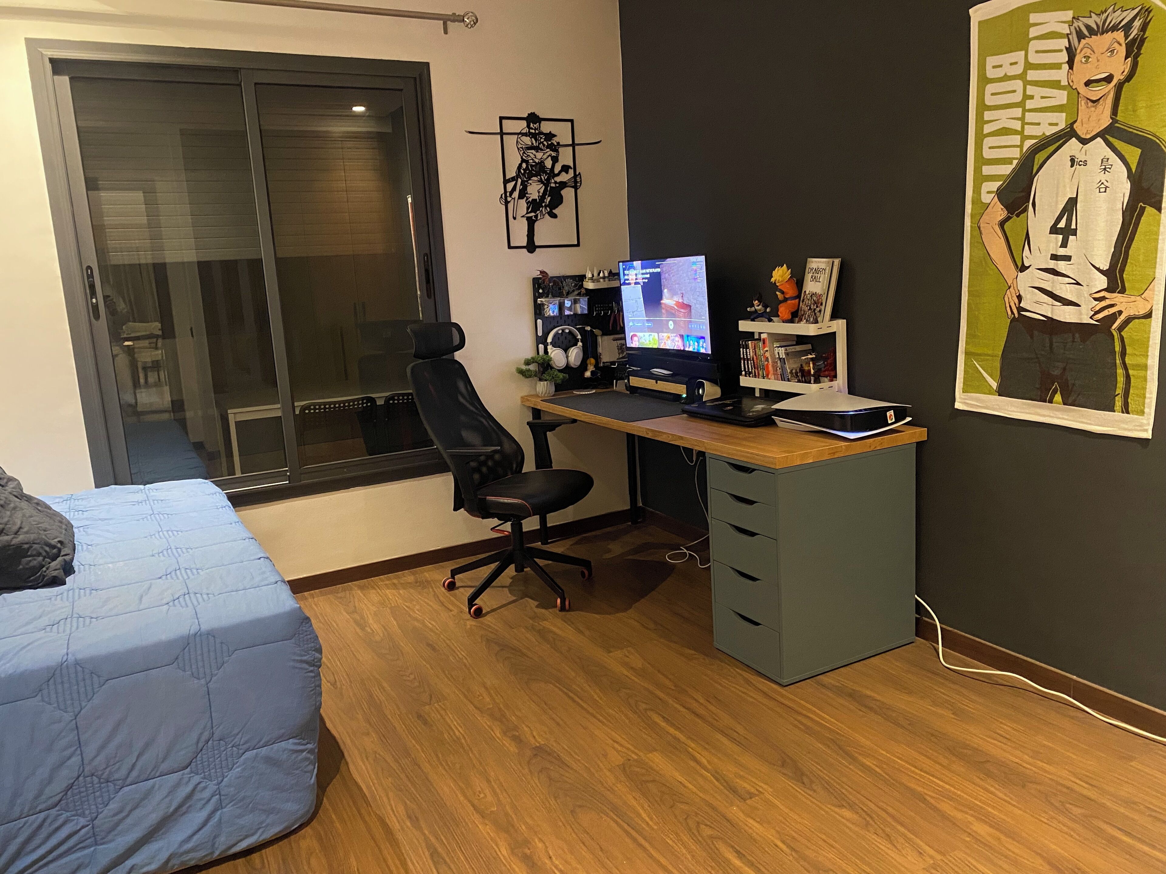 Een slaapkamer met een bed, een bureau met een computer en een raam.