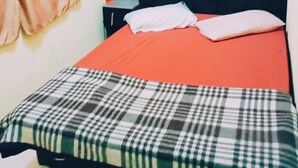Una cama con una colcha escocesa, un cabecero negro y una almohada blanca.