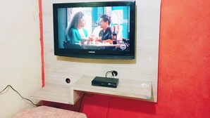 Un televisor montado en la pared con un estante de madera debajo.