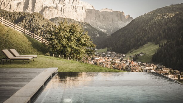 A mountain town with a pool overlooking a valley, a church, and a wooden fence. - Chalet Lavinia by My Villa Collection (Selva Gardena)