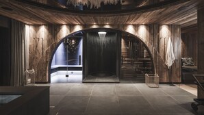 A spacious, modern lobby with a wooden interior, a large arched doorway, and a chandelier. - Chalet Lavinia by My Villa Collection (Selva Gardena)