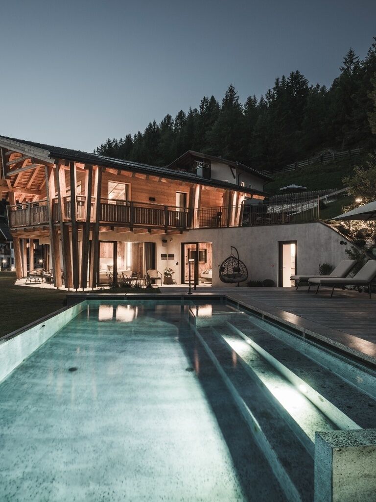 A two-story building with a pool, outdoor seating, and a balcony.