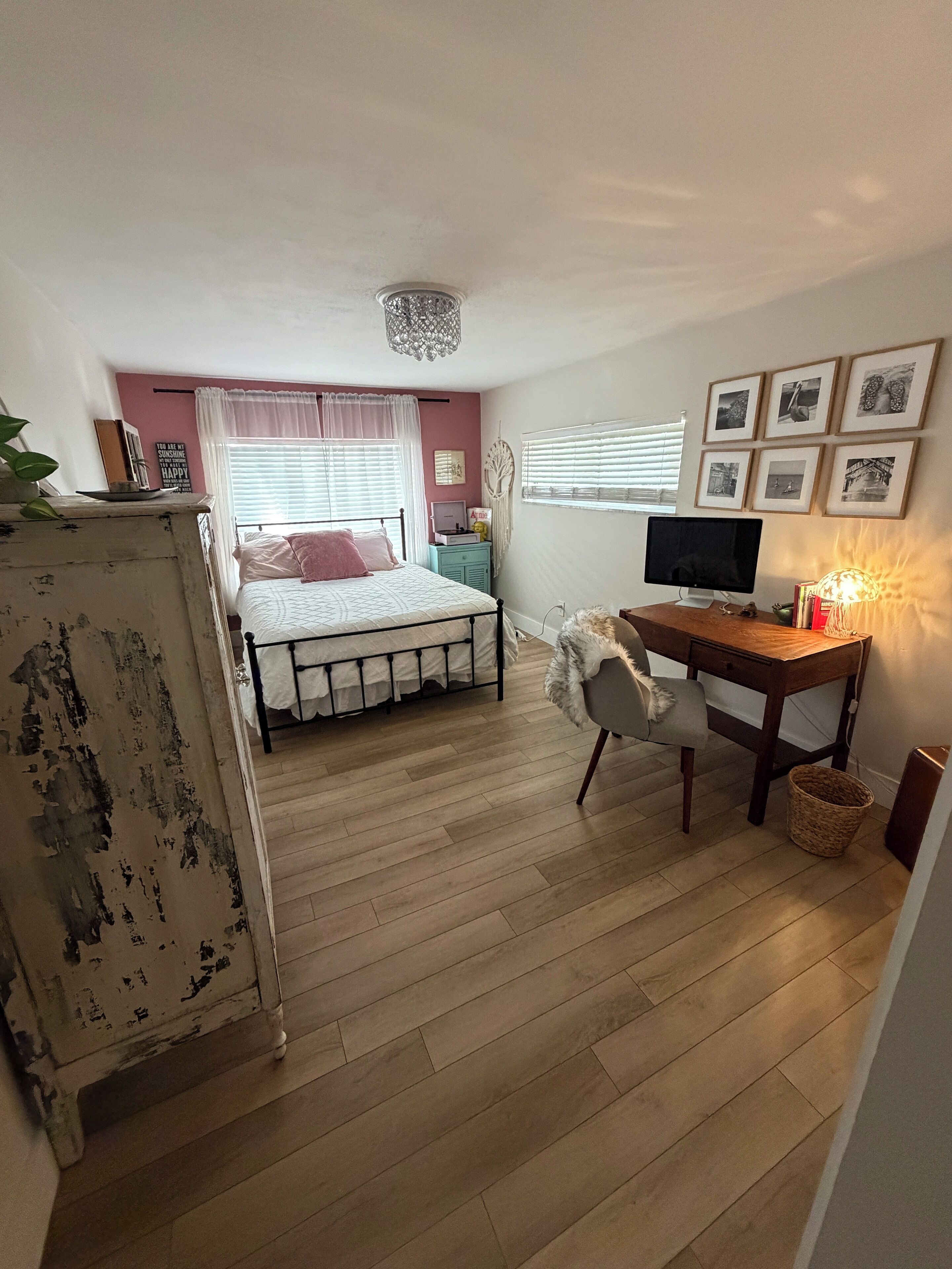 Un dormitorio con cama, escritorio, computadora y televisor.