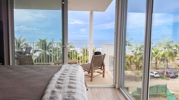 Un balcon avec un lit, une chaise et un ordinateur portable.