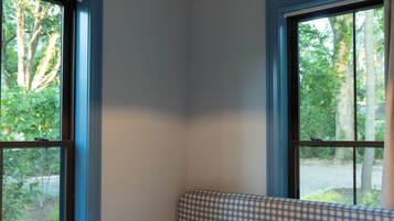 Quarto com uma janela grande, cabeceira xadrez e luminária pendente.
