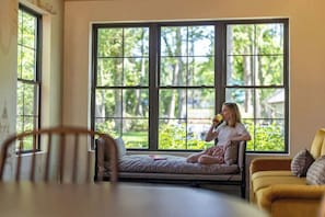 A room with large windows, a sofa, and a dining table. - Maison Foxglove - Petite Acres (New Buffalo)