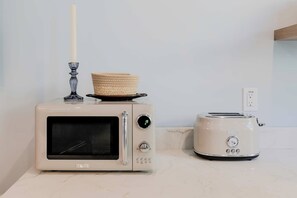 A kitchen with a white microwave oven, a toaster, and a candle holder with a basket on top.