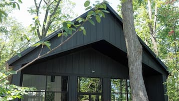 A modern house with a large glass front, surrounded by trees.