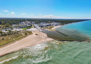 An aerial view of a coastal area with a beach, a marina, and residential buildings. - Bellflower - Cozy One Bedroom Villa at Petite Acres (New Buffalo)