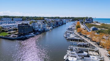A marina with boats docked along a river, surrounded by residential buildings and a beach.