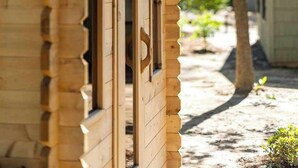 A wooden cabin with a gabled roof, a window, and a door.