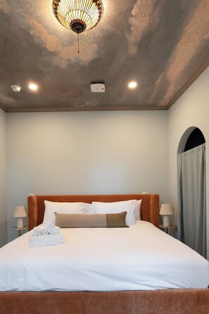 A hotel room with a bed, a ceiling light fixture, and a wall-mounted device. - Bellflower - Cozy One Bedroom Villa at Petite Acres (New Buffalo)