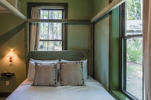 Una habitación con cama, lámpara y ventana con cortinas.