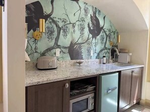 A kitchen with a microwave, toaster, and a small refrigerator.