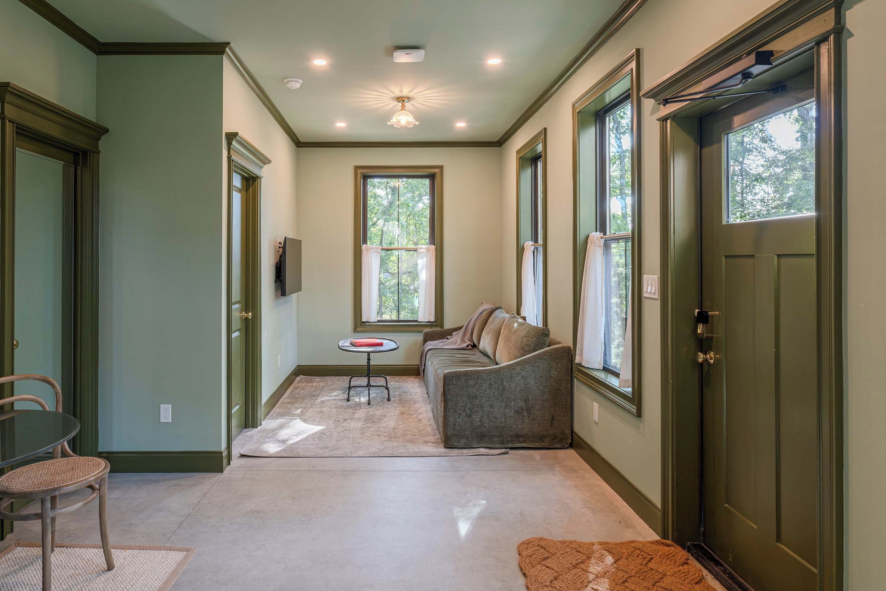A hallway with a sofa, a small table, and a door.
