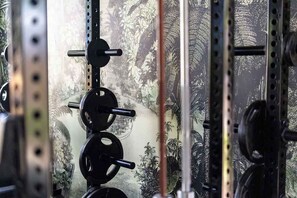 A weightlifting area with a wall-mounted rack, barbells, and weight plates.