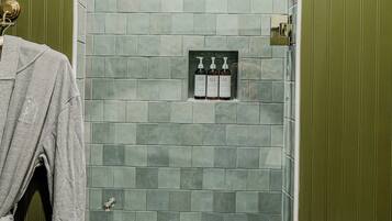 A bathroom with a tiled shower area, a towel rack, and a toilet paper holder.