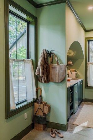 Una habitación con ventana, un abrigo de piel colgado, una cesta de mimbre y un par de zapatos.