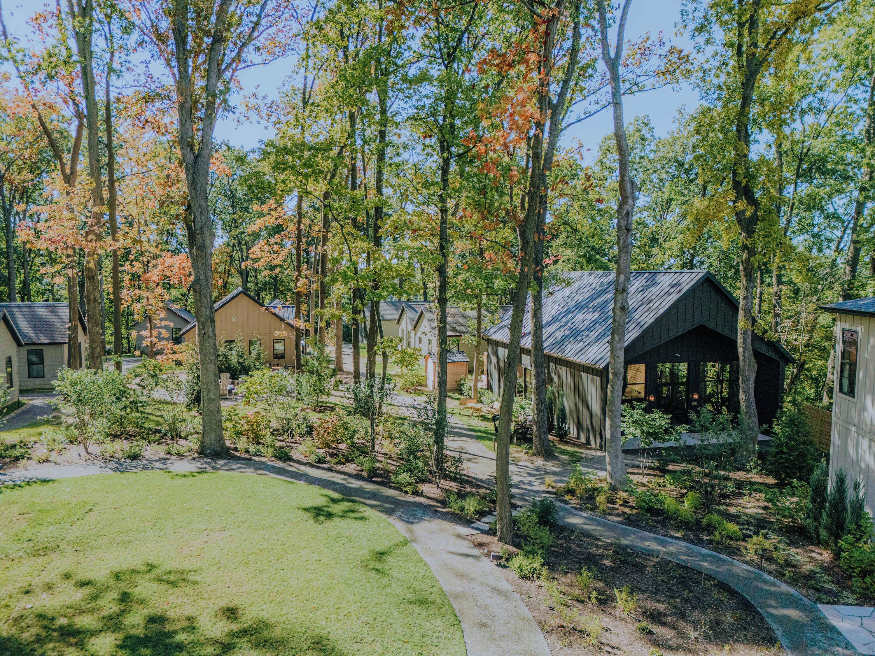 A residential area with multiple houses, a covered outdoor seating area, and a well-maintained lawn.
