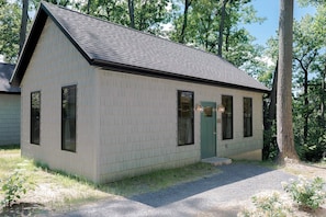 A small, single-story building with a sloped roof, a front door, and multiple windows.