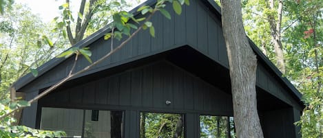 A modern house with a large glass front, surrounded by trees.