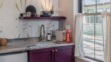 A kitchen with a window, a sink, and a trash can.