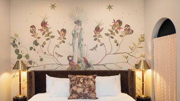 A bedroom with a large bed, two bedside lamps, a wall mural, and a ceiling light fixture.