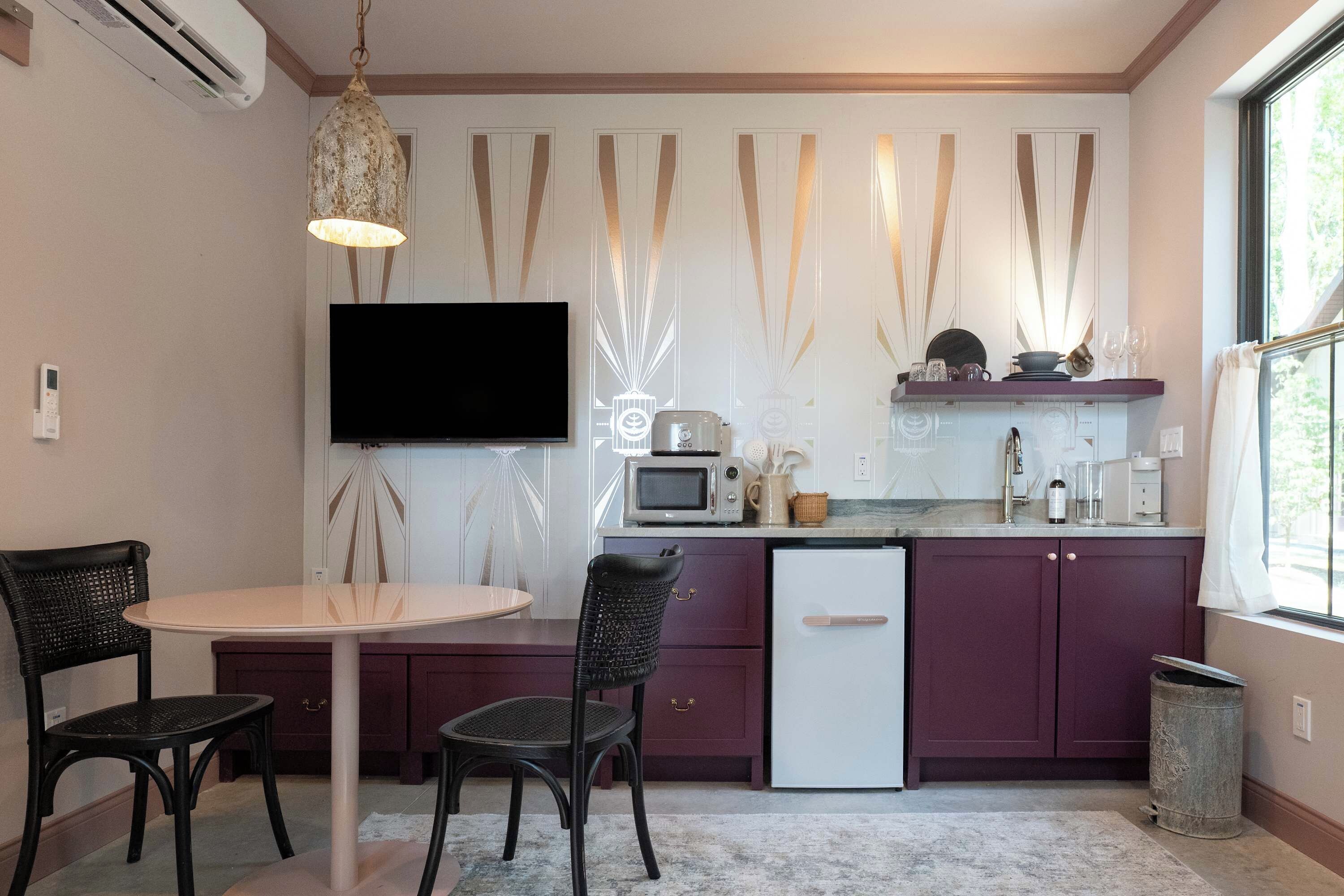 A compact kitchen with a dining area, a flat-screen TV, and a small refrigerator.