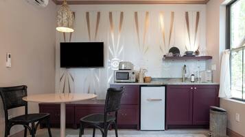 A compact kitchen with a dining area, a flat-screen TV, and a small refrigerator.