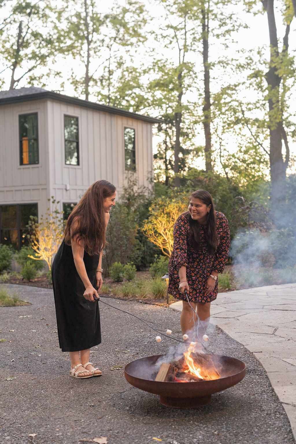 Two people roasting marshmallows over a fire pit outdoors.