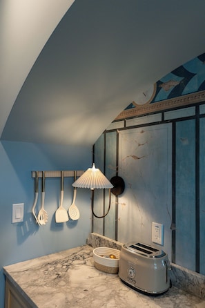 A kitchen with a marble countertop, a toaster, and a wall-mounted light fixture.