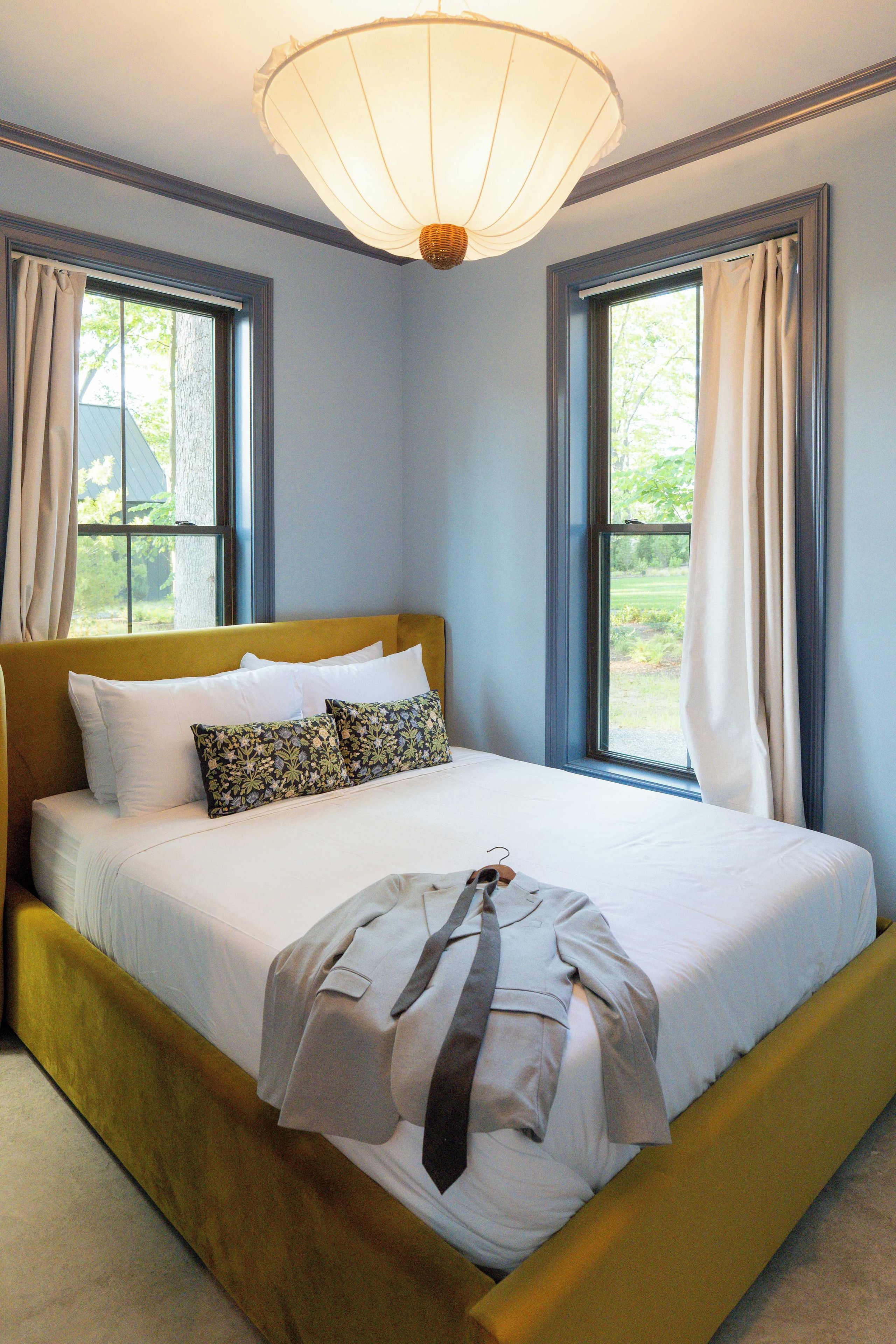 A bed with a headboard, a bedside table, and a hanging light fixture.