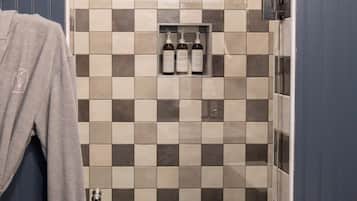 Un baño con pared de baldosas a cuadros, zona de ducha y un perchero.