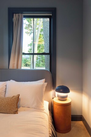 A bedroom with a bed, a bedside lamp, and a window with curtains.