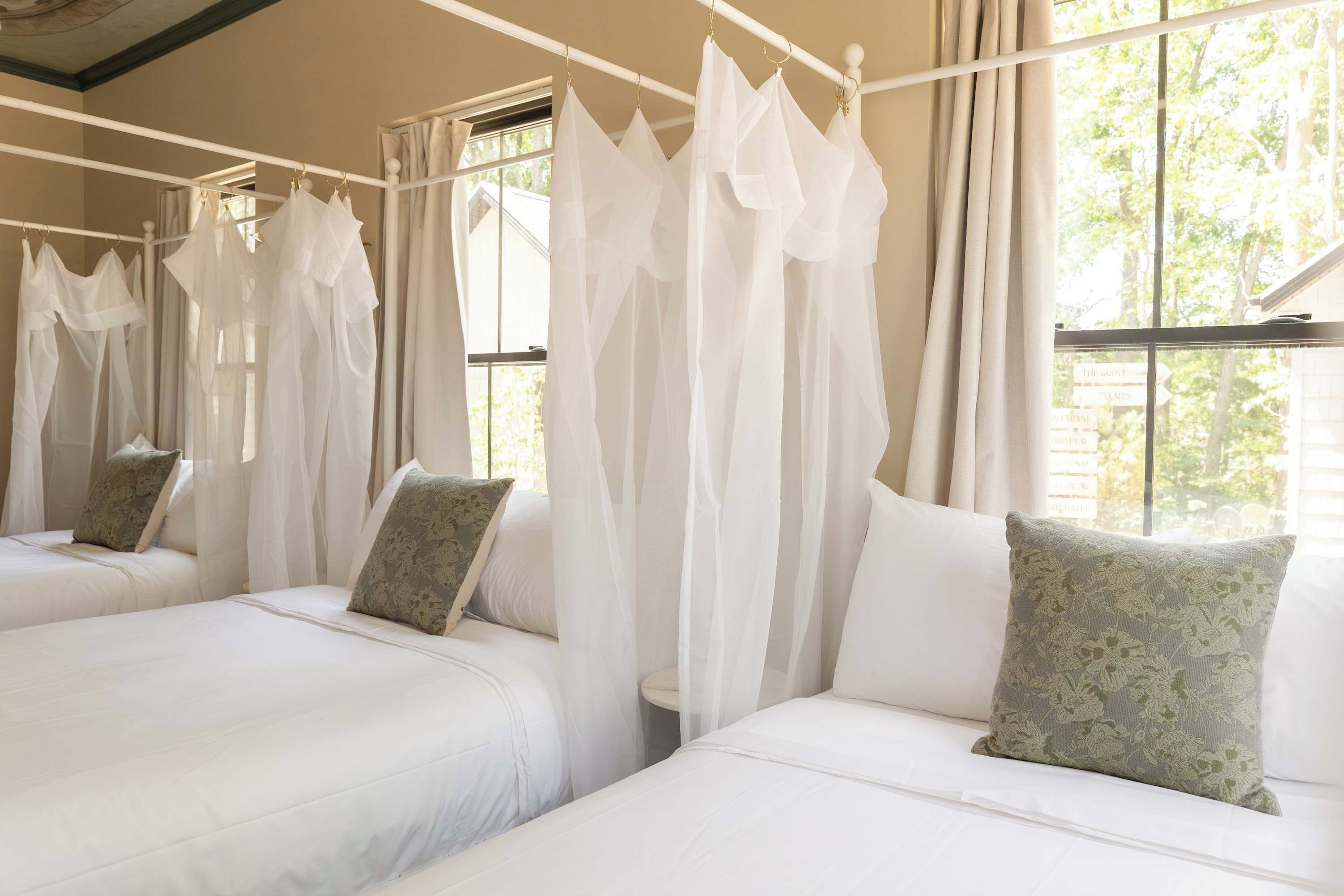 A hotel room with two beds, each with white bedding and green floral pillows.