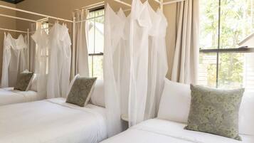 A hotel room with two beds, each with white bedding and green floral pillows.