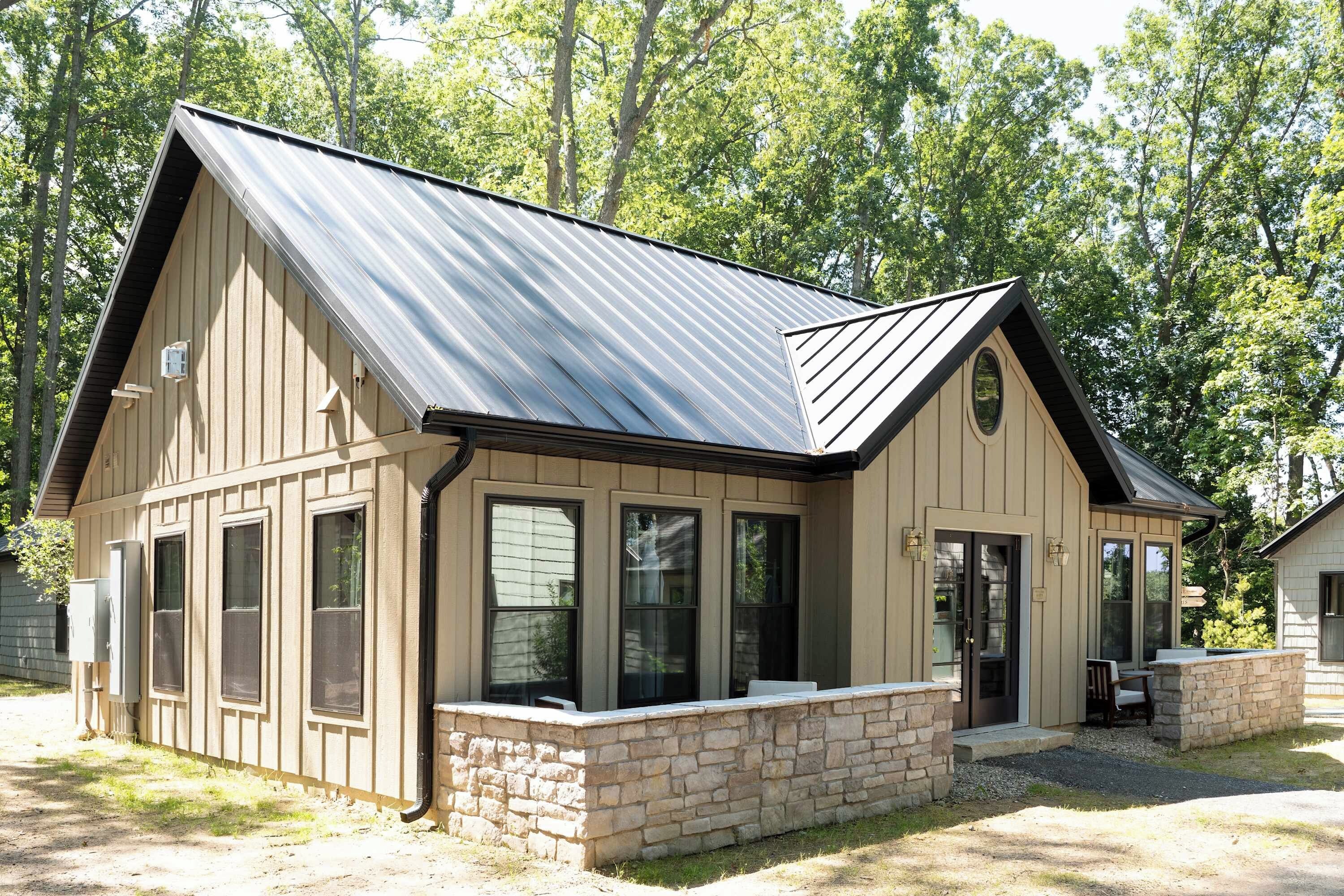 A two-story building with a gabled roof, large windows, and a stone foundation.
