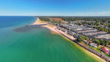 An aerial view of a coastal town with a marina, residential areas, and a beach.