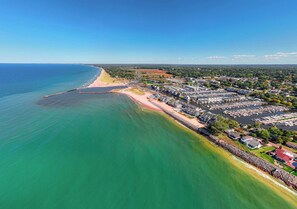 Vista aérea de un pueblo costero con un puerto deportivo, zonas residenciales y una playa.