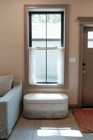 A room with a window, a bench, a door, and a light-colored wall.