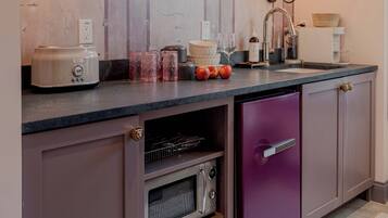 Eine Küche mit Backofen, einem violetten Kühlschrank und einer Arbeitsfläche mit verschiedenen Gegenständen.