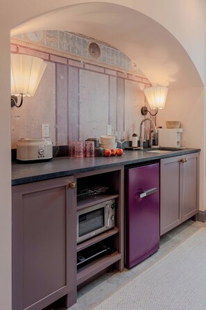 Eine Küche mit Backofen, einem violetten Kühlschrank und einer Arbeitsfläche mit verschiedenen Gegenständen.