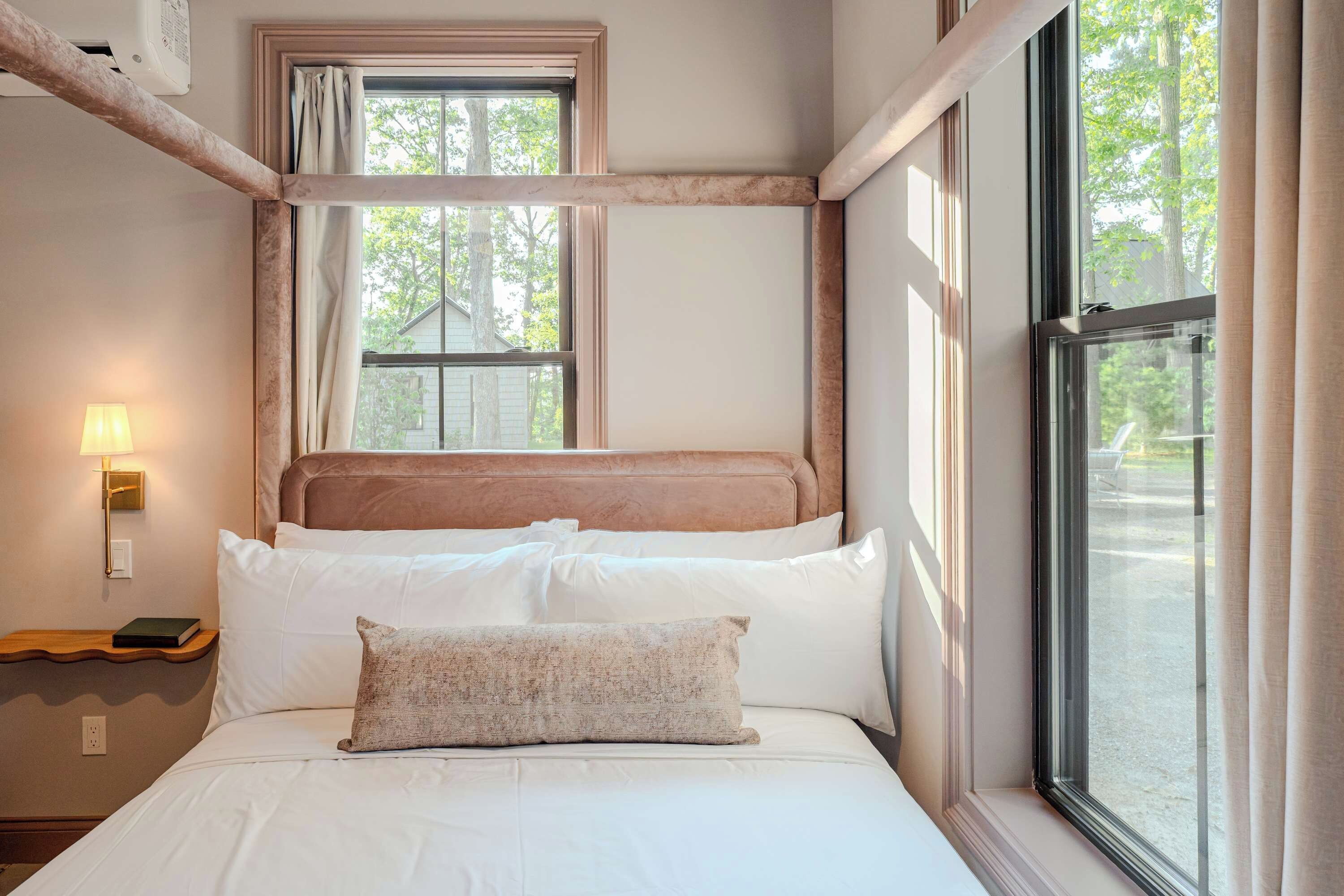 Una camera da letto con un letto, una finestra e un comodino con una lampada.